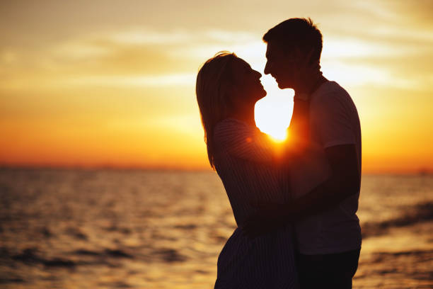 Young happy couple on seashore in the lights of sunset.